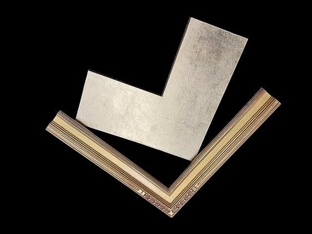 Two L-shaped pieces of picture frame molding, one silver-toned and one with decorative gold and brown detailing.