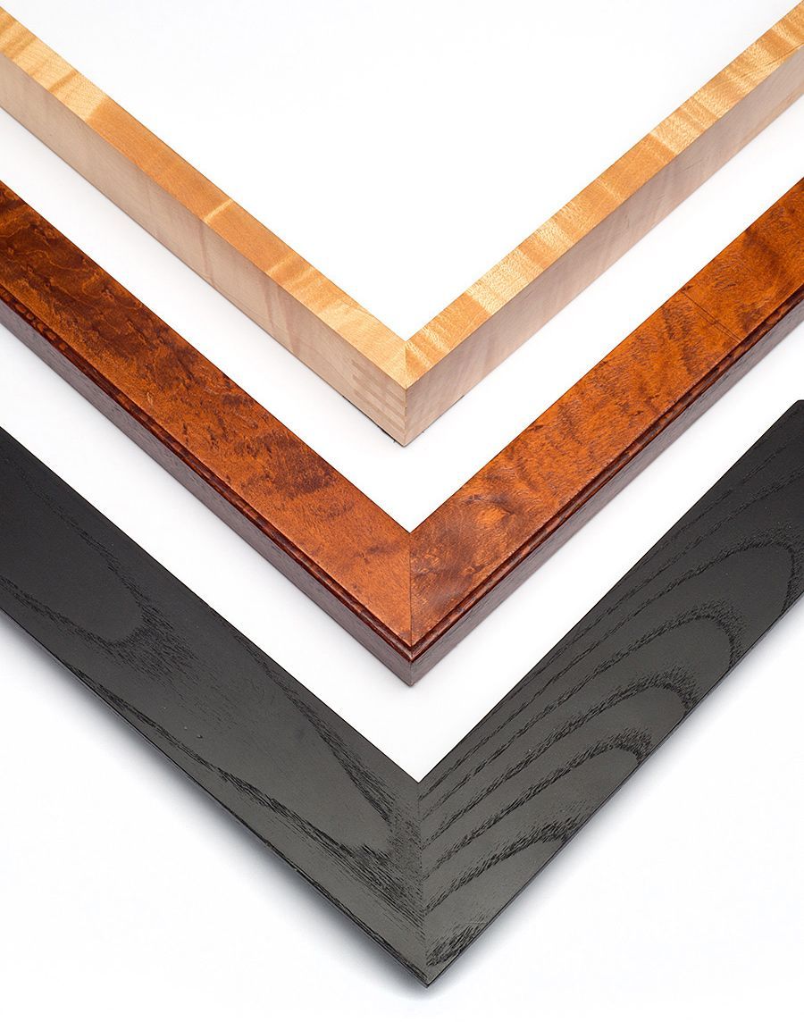 Three nested picture frame corners: one light natural wood, one reddish-brown burl, and one textured black wood.