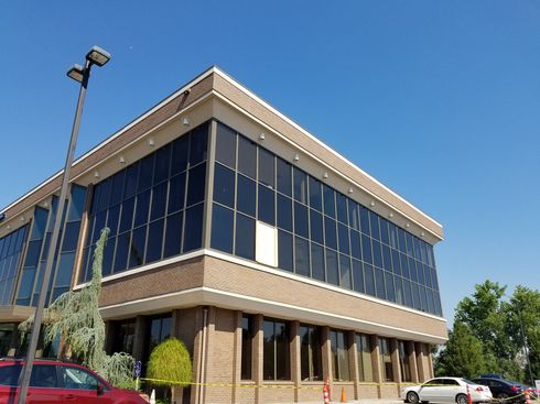 A large building with a lot of windows and a red car parked in front of it.