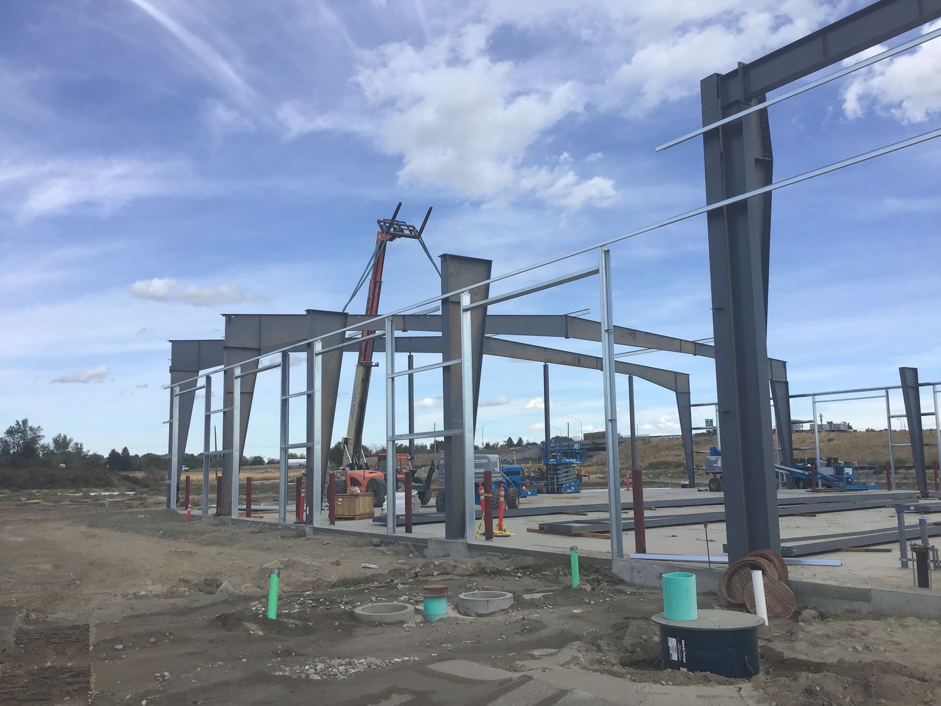 A large metal structure is being built in a dirt field.