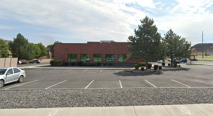 A white car is parked in front of a brick building