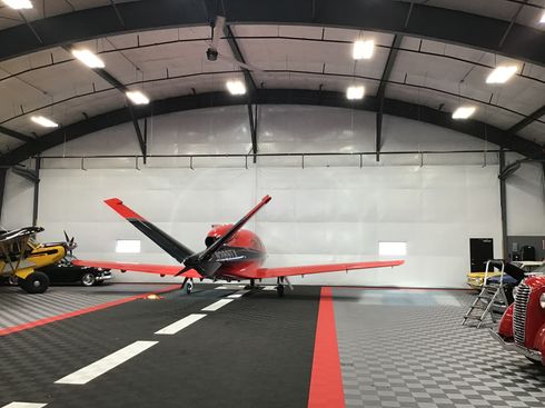 A small red airplane is parked in a hangar.