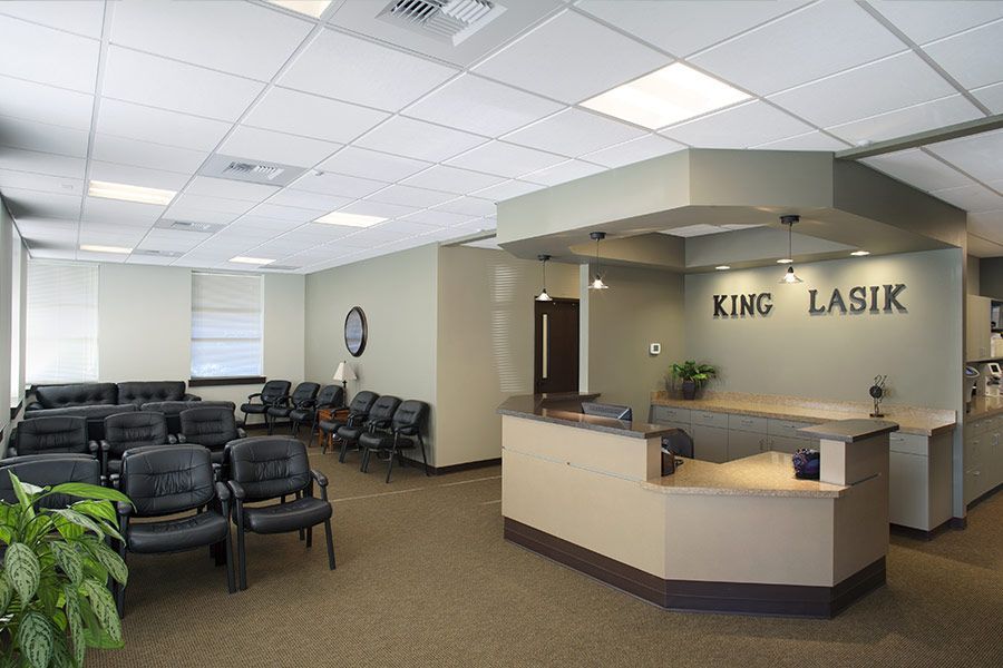 A waiting room with a reception desk and a sign that says king lasik