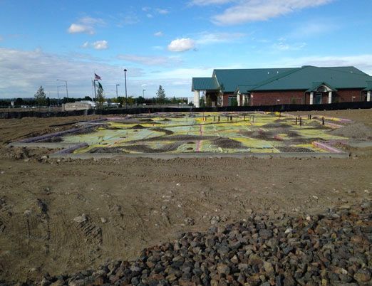 A large building is being built in the middle of a dirt field.