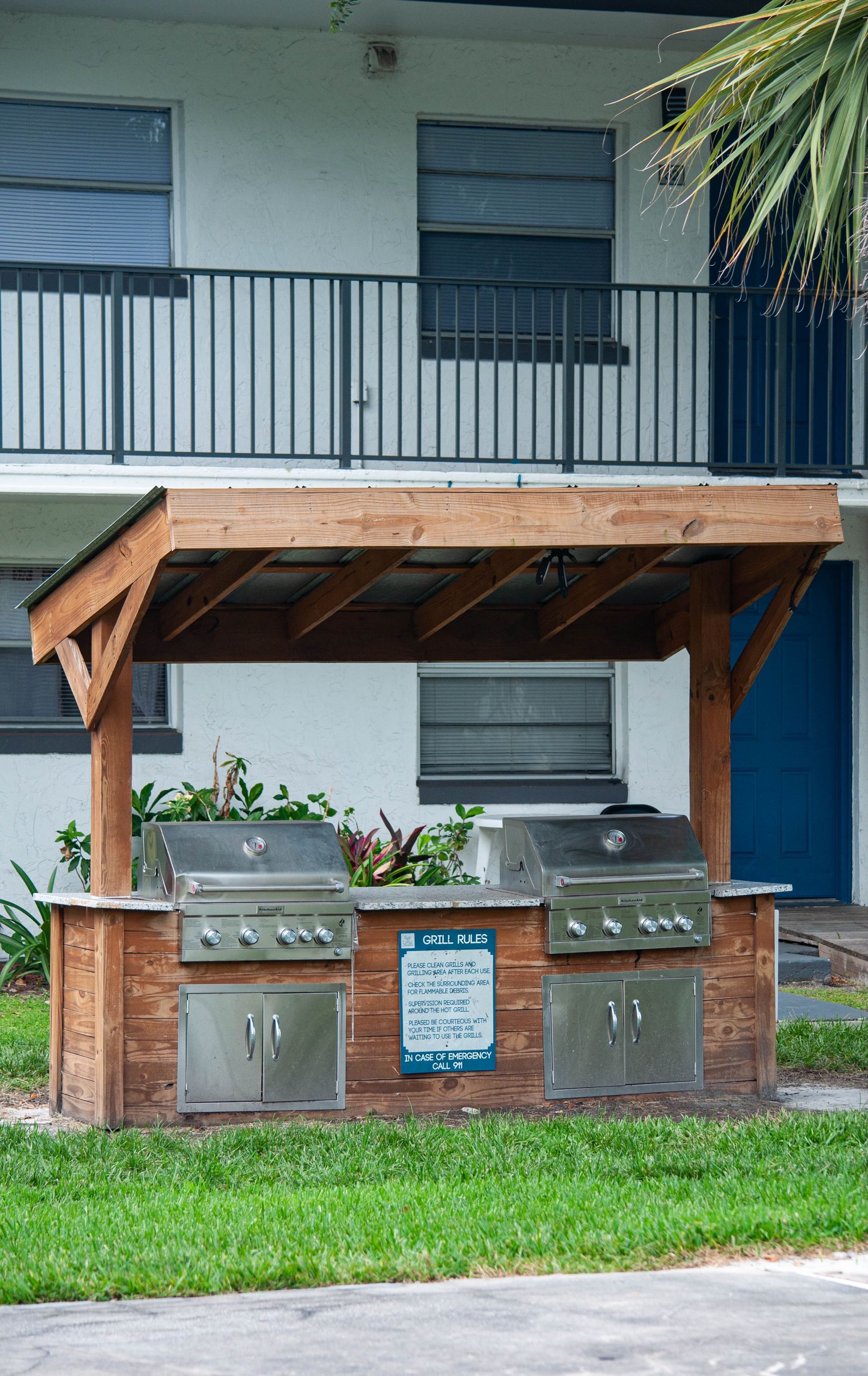A grill is sitting under a wooden outdoor kitchen infront