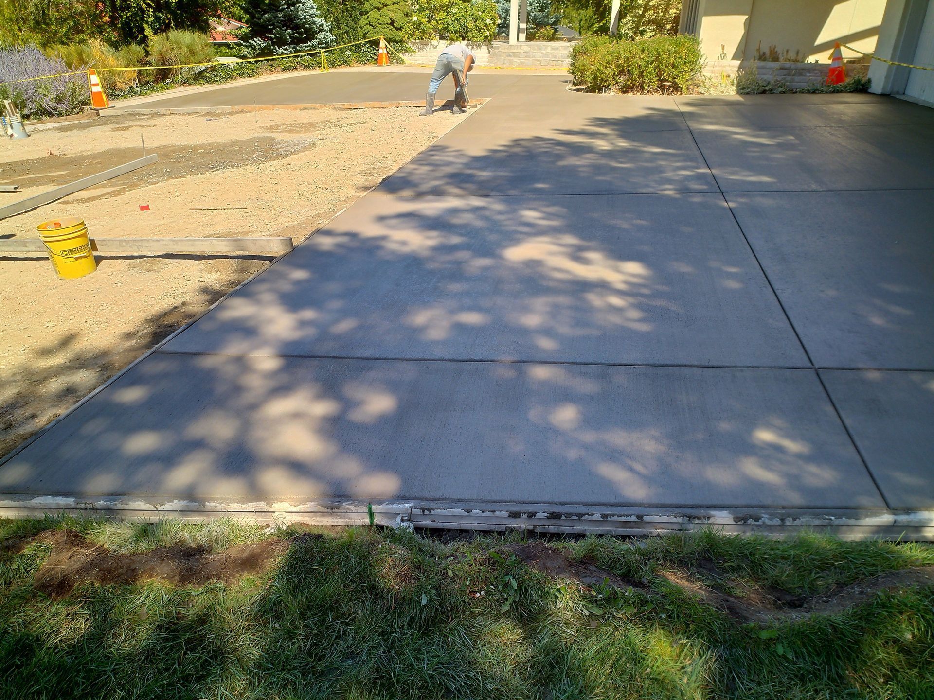 A Man is Working on a Concrete Driveway in Front of a House – Reno, NV – Concreteworks LLC 