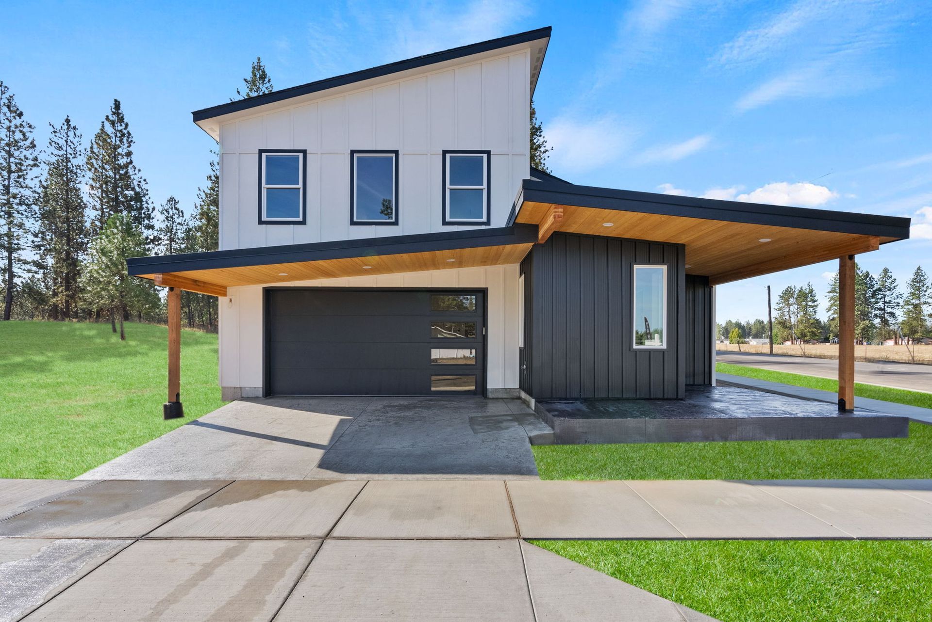 A white house with a black garage door is sitting on top of a lush green field.