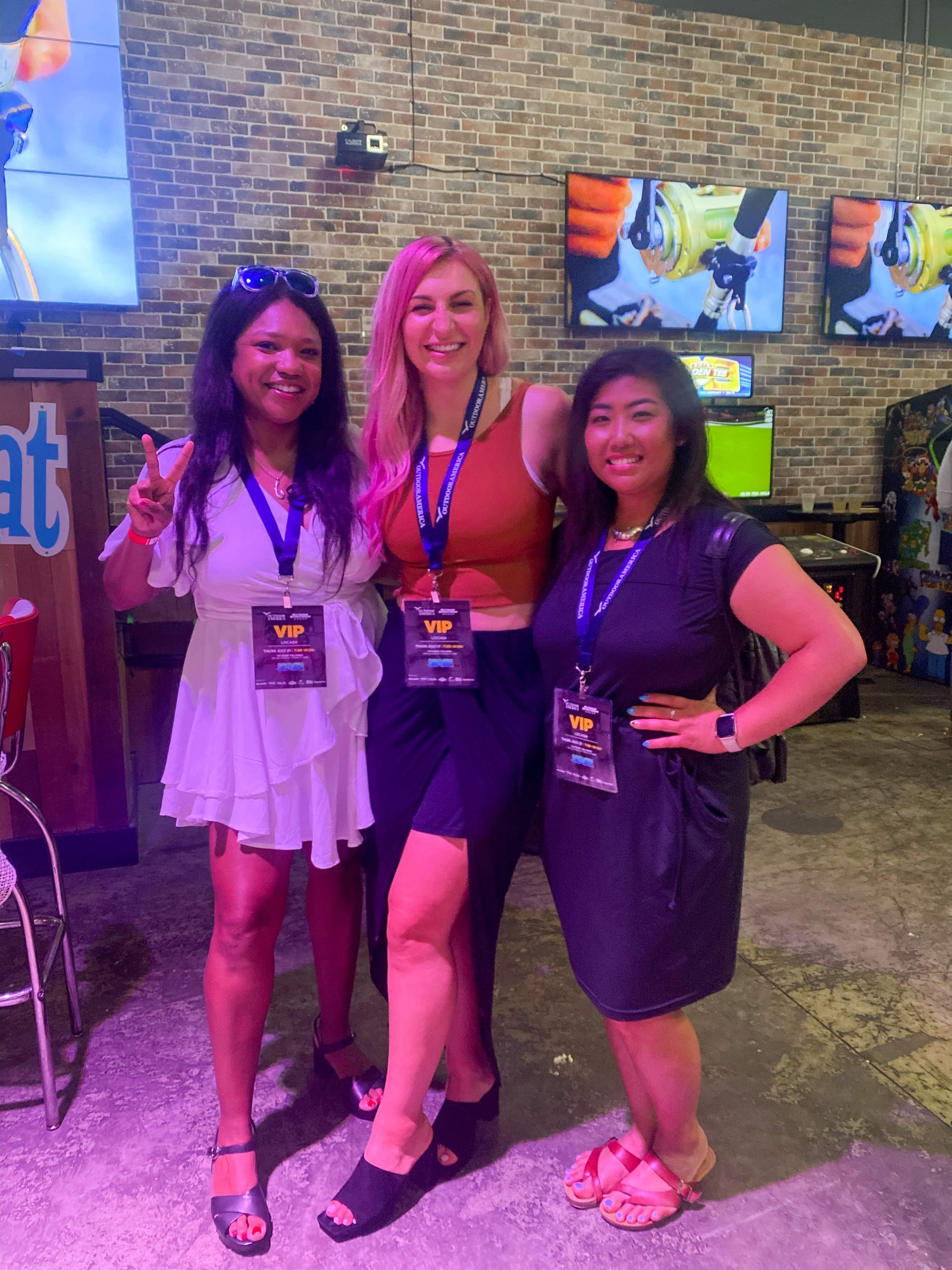 three women posing for a picture with one wearing a vip lanyard