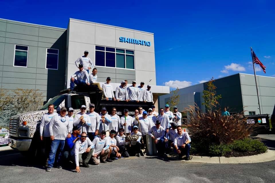 a group of men pose in front of a building that says shimano