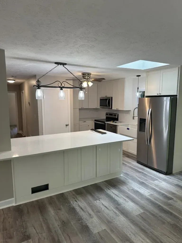 A kitchen with white cabinets , stainless steel appliances , and a large island.
