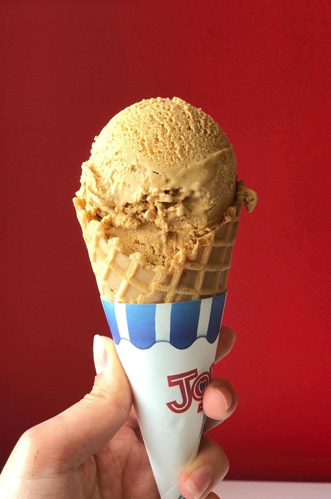 A person is holding an ice cream cone with a red background