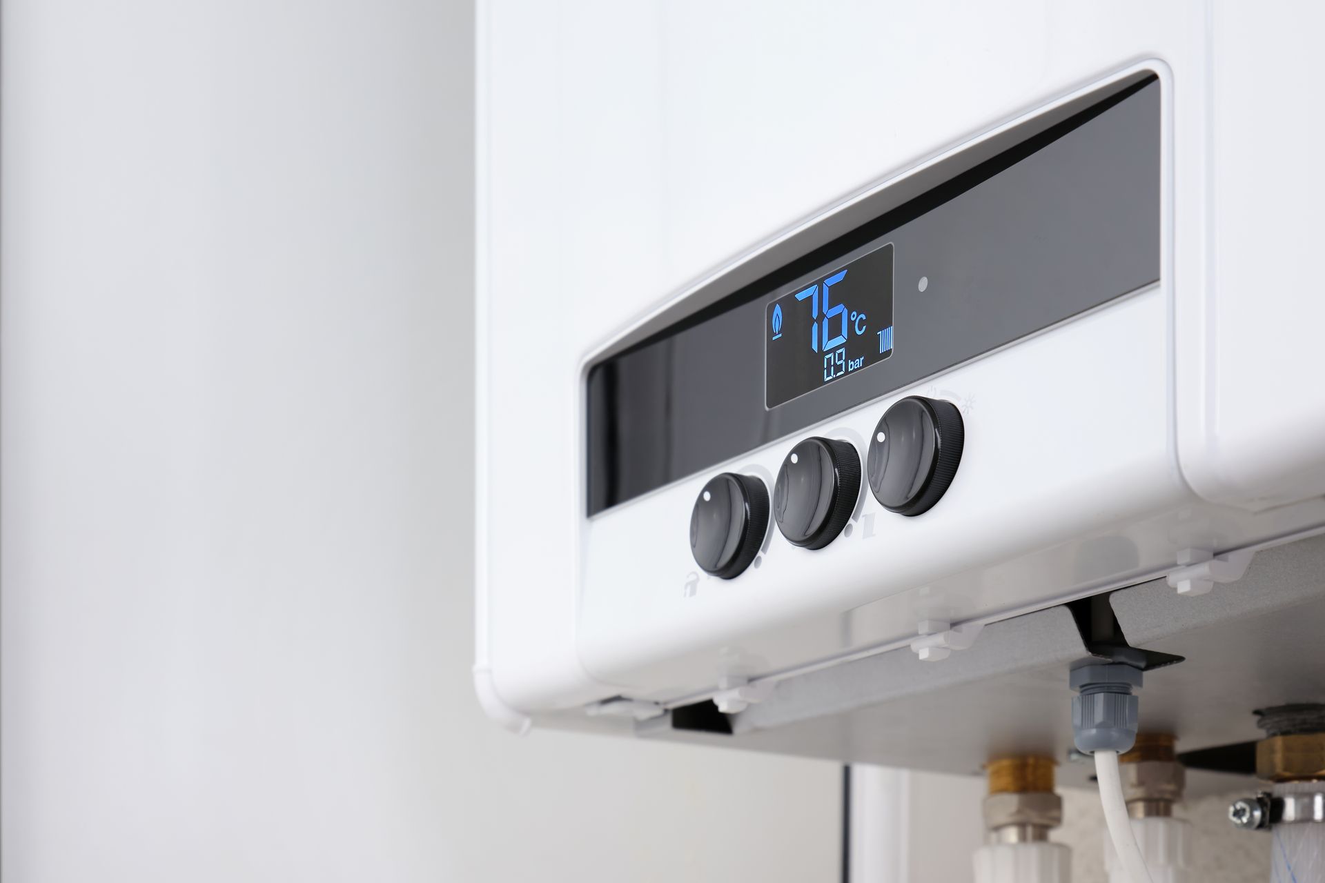 White wall-mounted gas boiler with control knobs and digital display showing 76 degrees.
