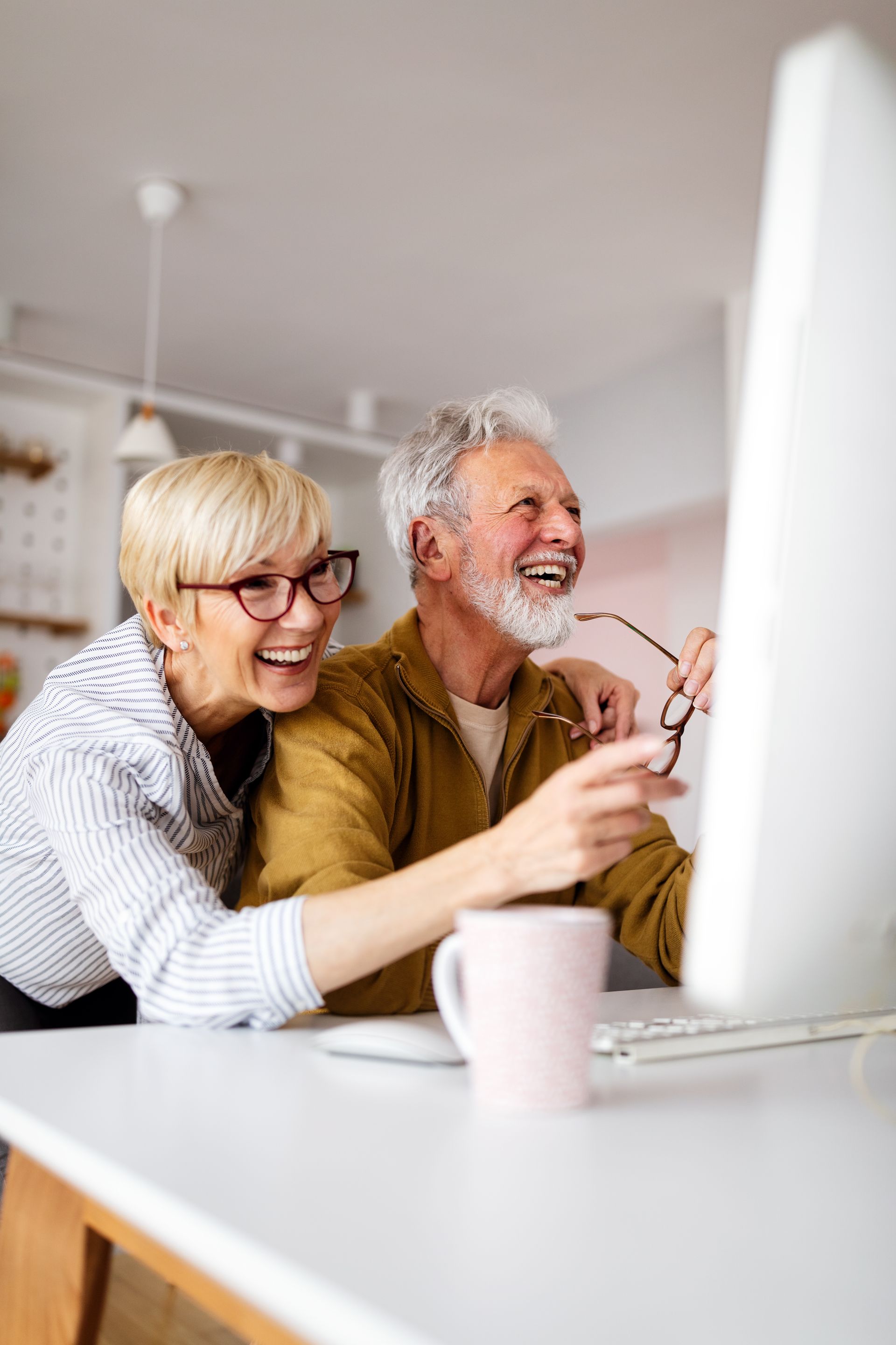 Senior woman helping senior man to use computer.