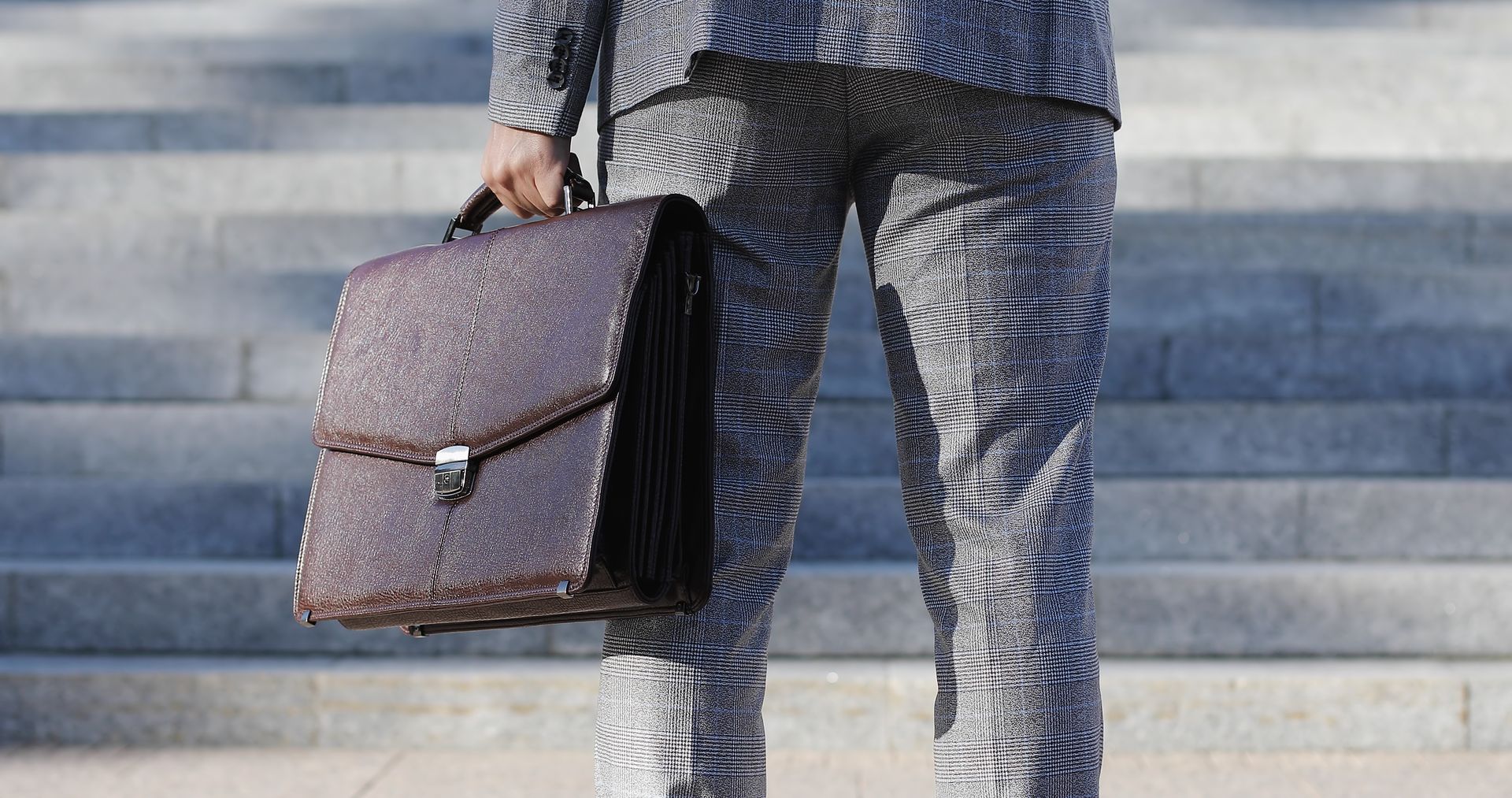 Unrecognizable businessman or lawyer in formal suit with briefcase goes upstairs in centrelink offices of company or in the building of state authority.