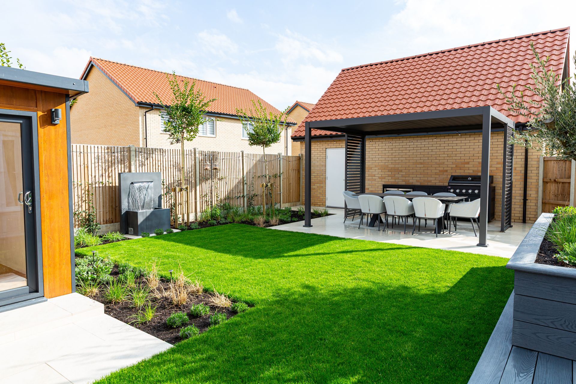 Modern backyard with a patio, dining set, lawn, water feature, and a shed.