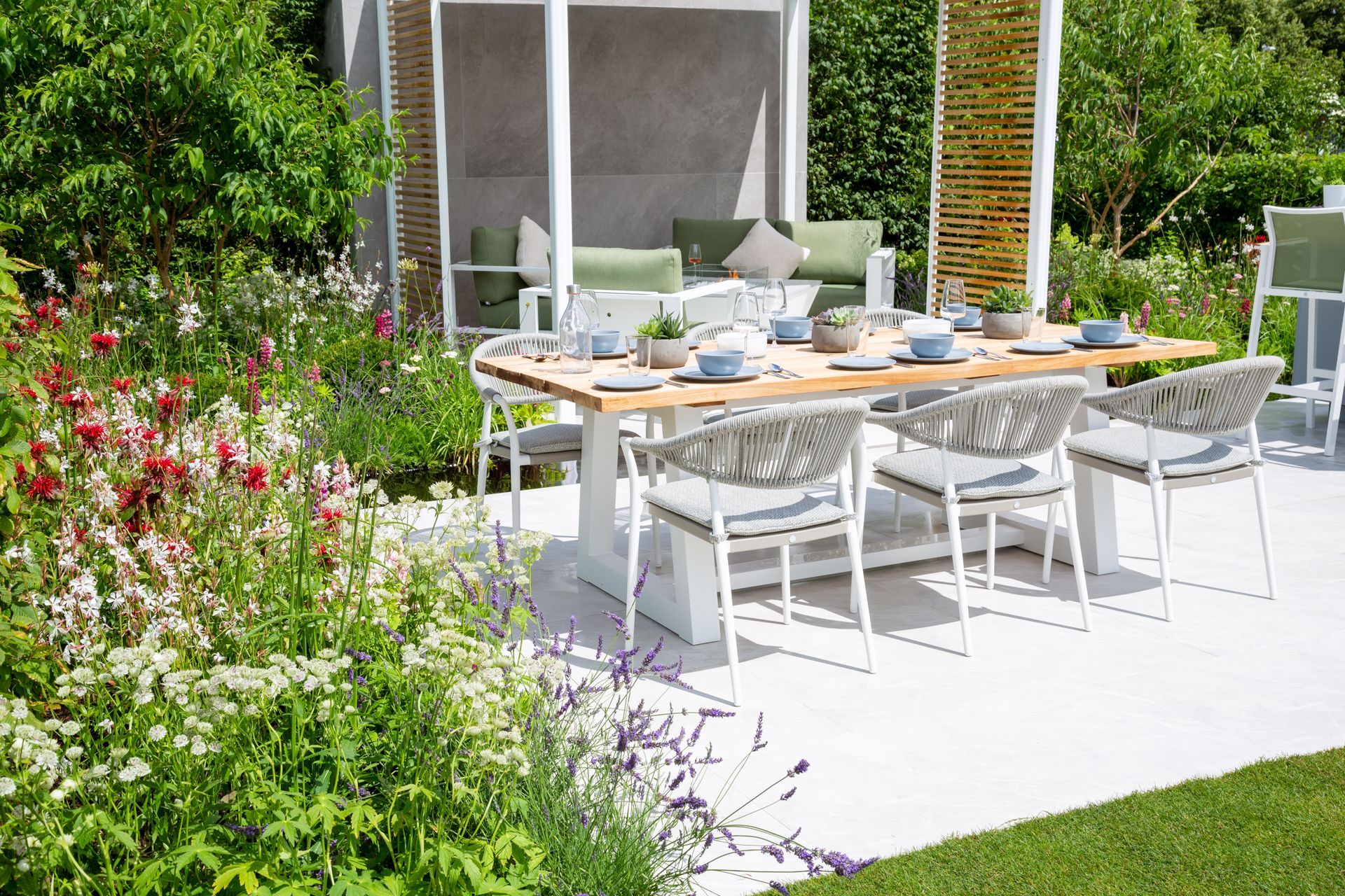 Outdoor dining area with a table, chairs, and garden with flowers.