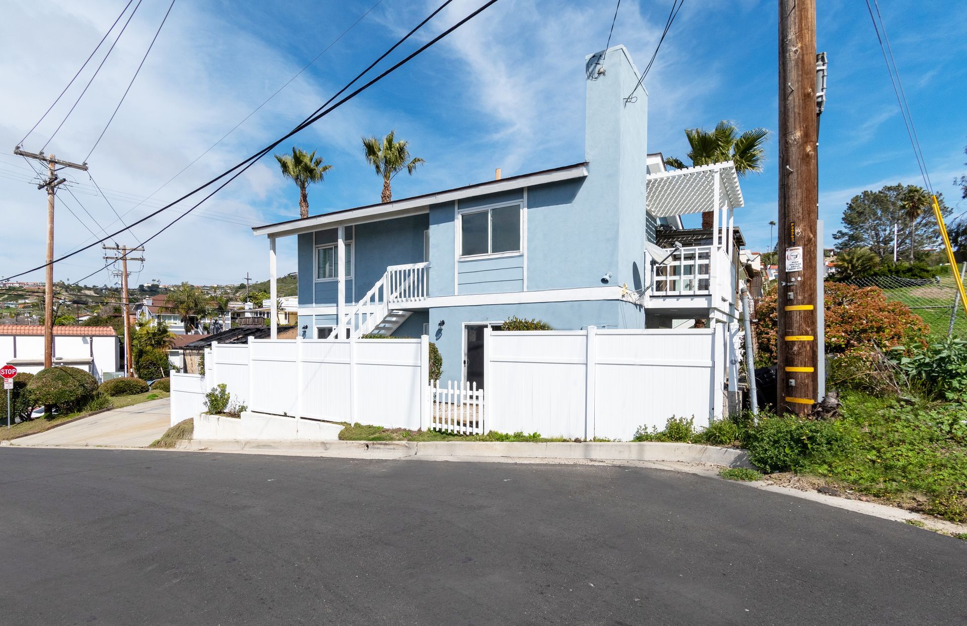 A blue house with a white fence and stairs