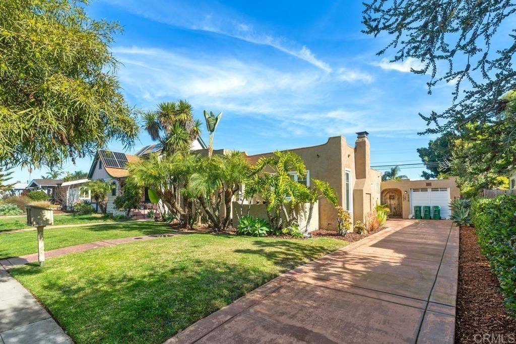 A large house with a lush green lawn and a driveway leading to it.