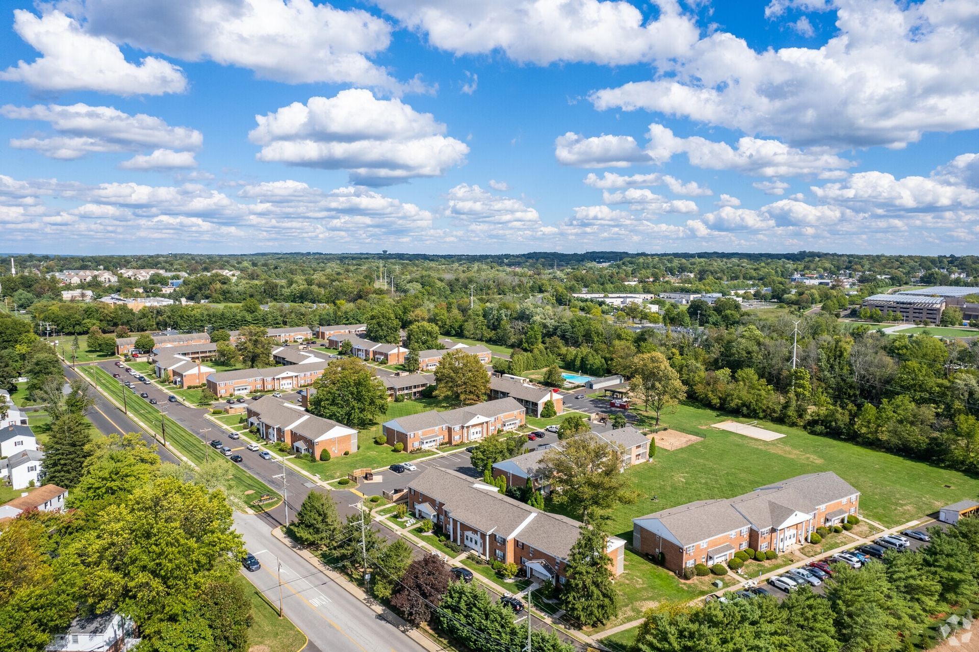 Aerial view of a suburban apartment community with brick buildings, roads, and green spaces.
