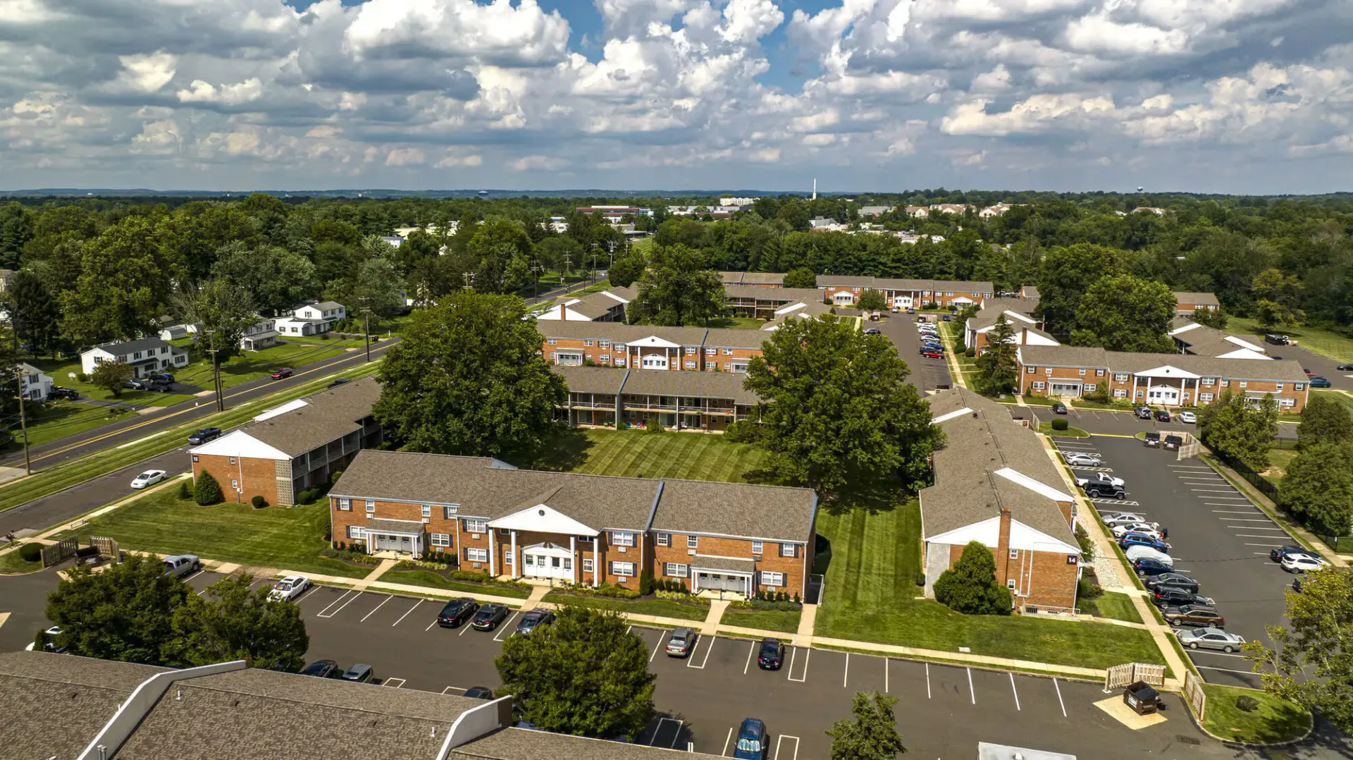Aerial view of brick apartment buildings, parking lots, and green lawns.