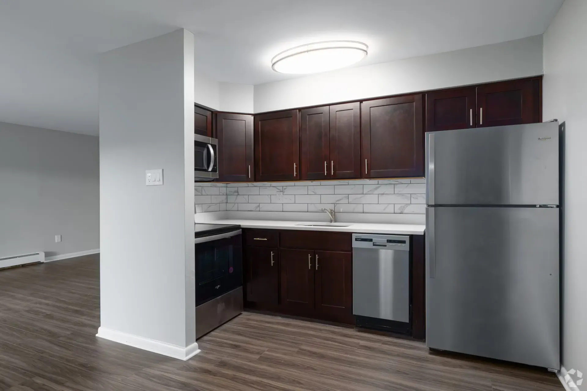 Kitchen with dark wood cabinets, stainless steel appliances, and white countertops.
