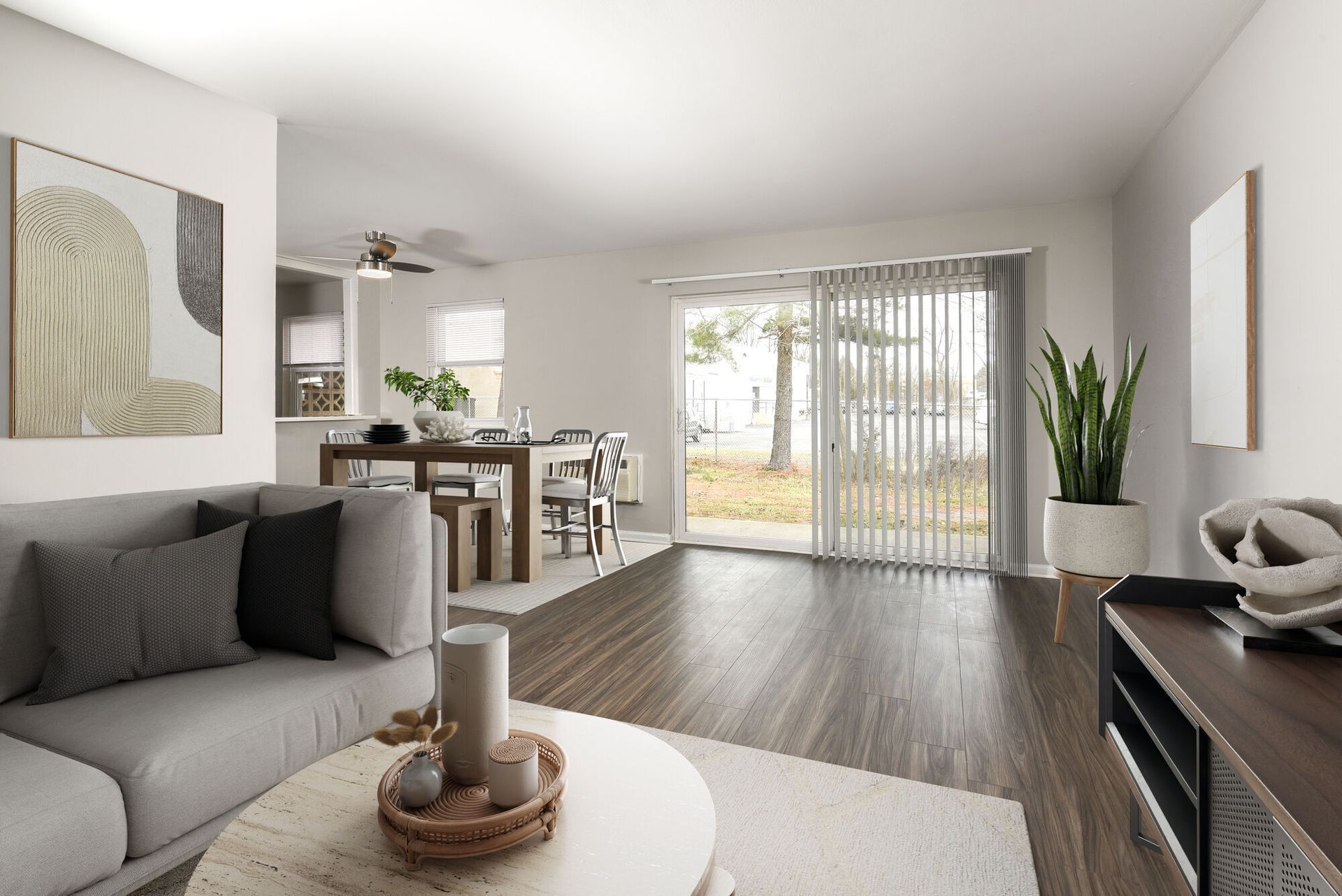Open-plan living area with a gray sofa, dining table, and sliding glass doors.