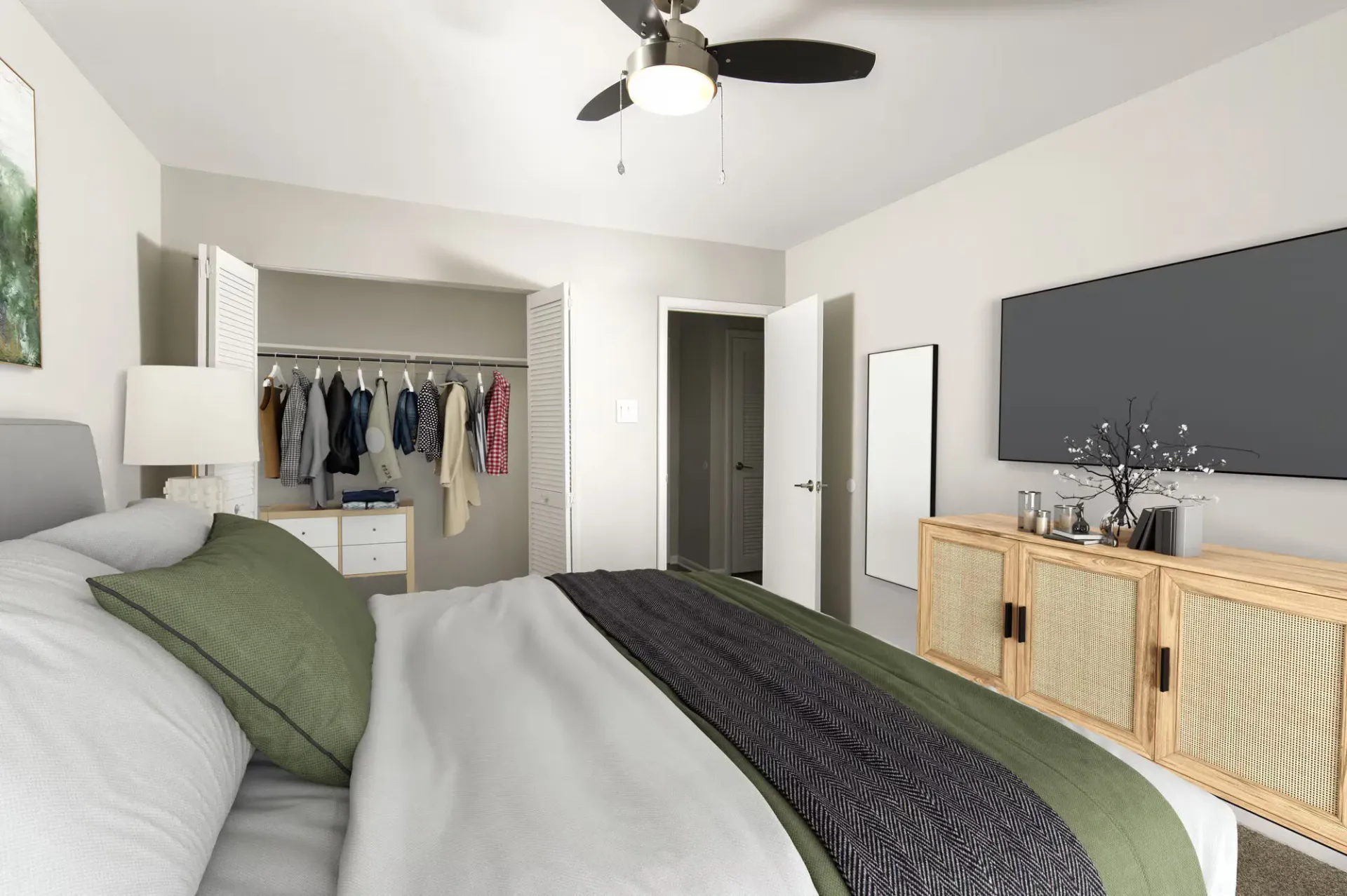 Bedroom in apartment with bed, open closet of clothes, dresser, and wall-mounted TV.