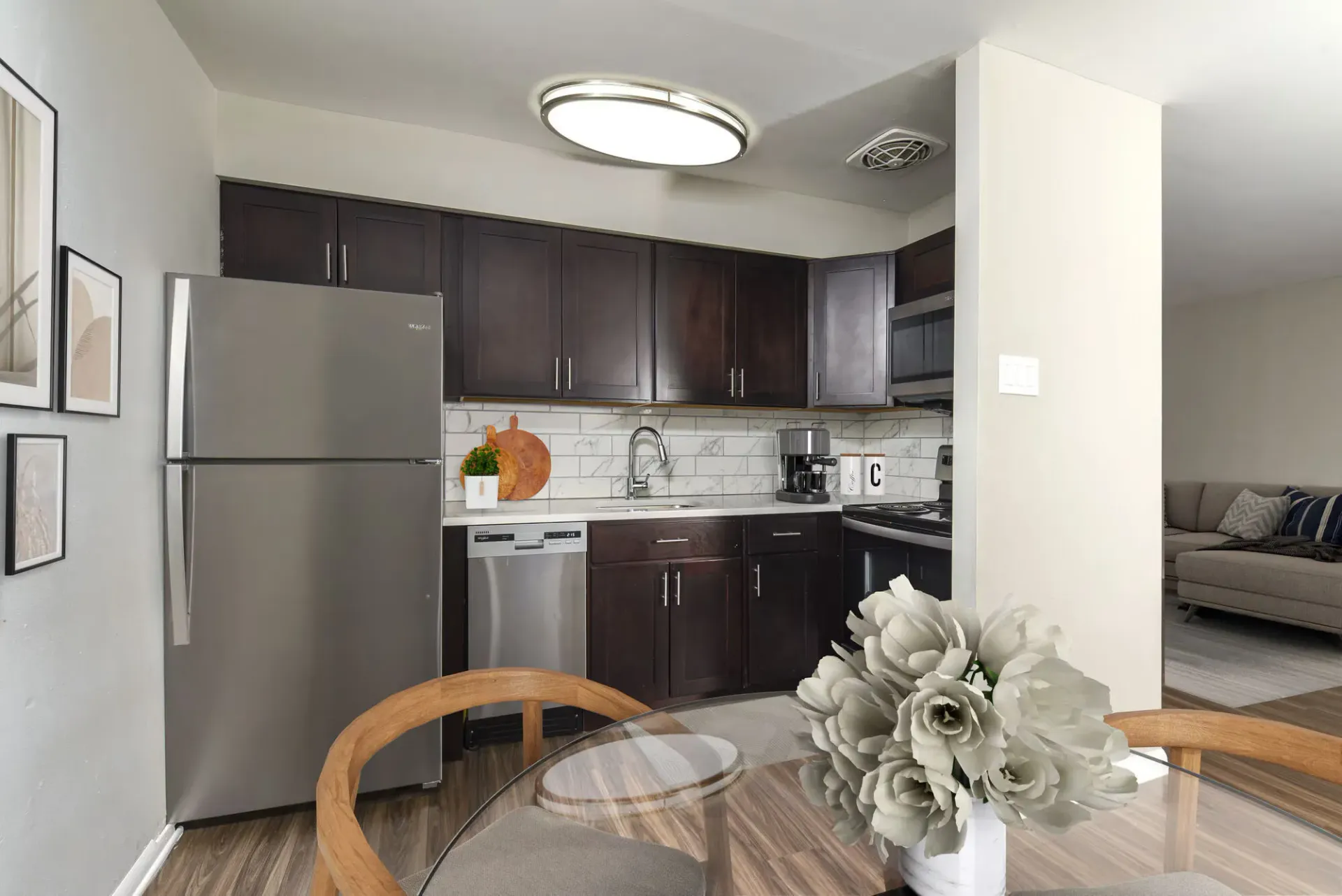 Modern kitchen with dark wood cabinets, stainless steel fridge and appliances, and white marble backsplash.
