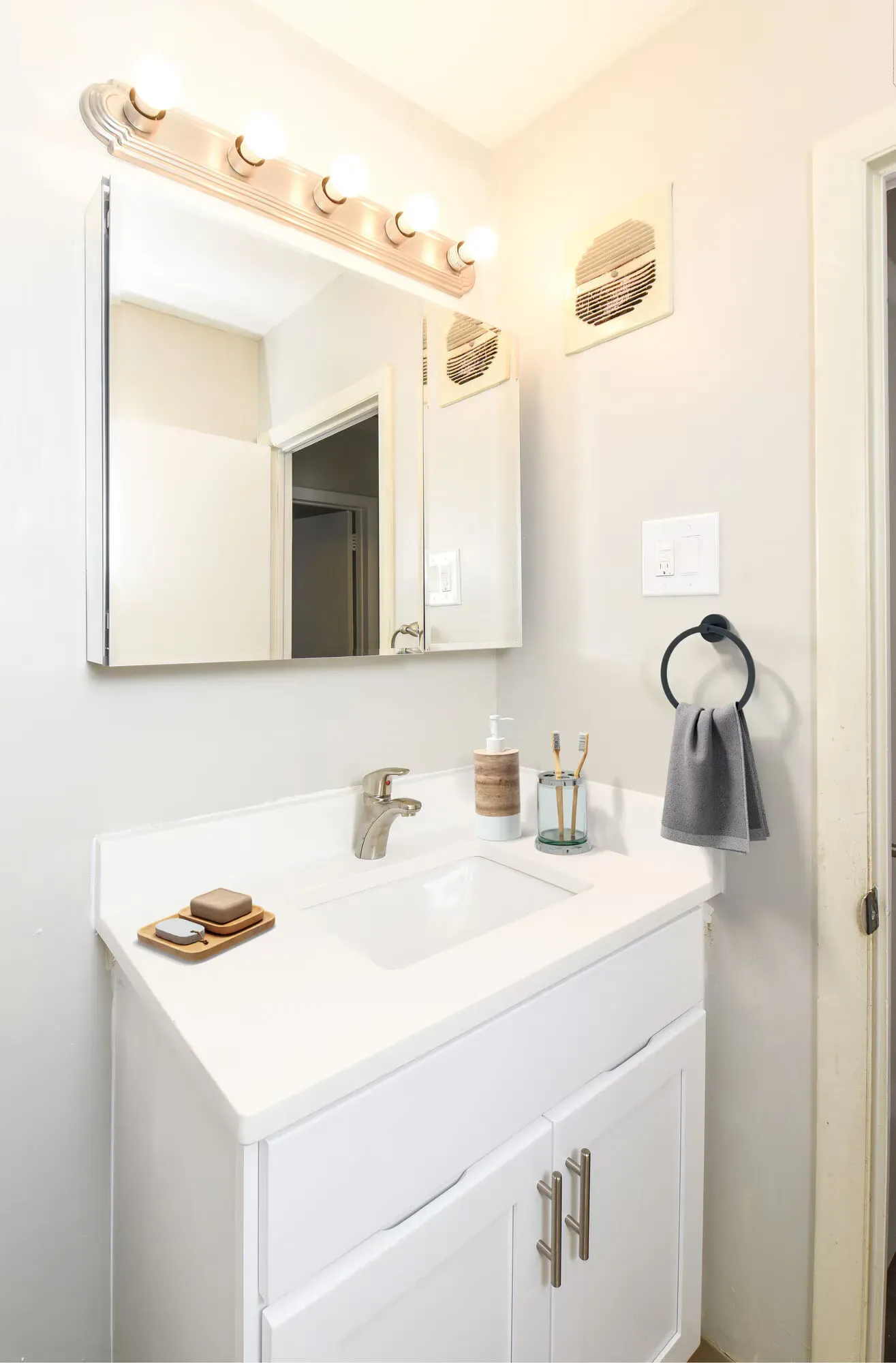 White bathroom vanity with sink, mirror, and towel ring.