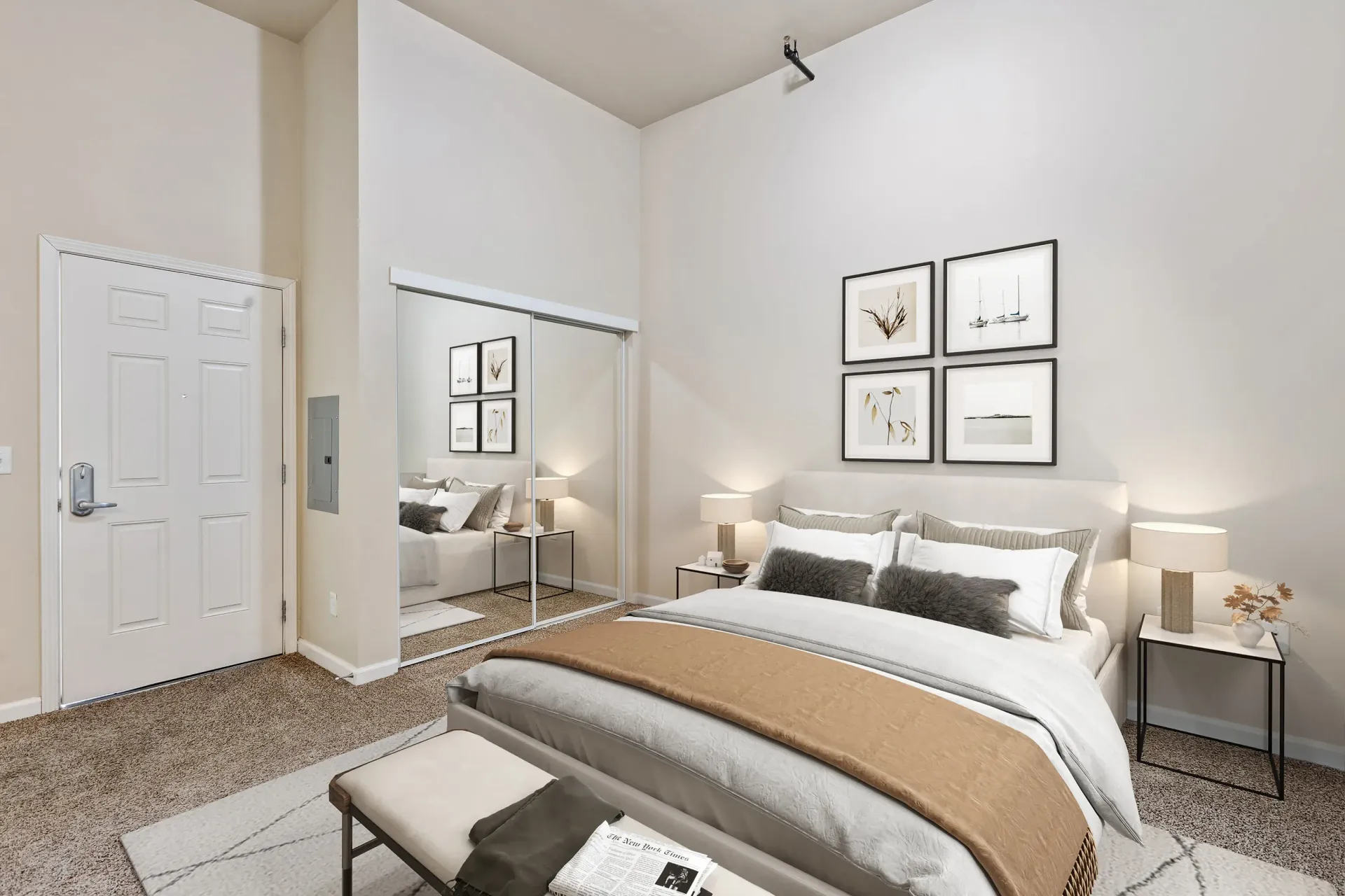 Bedroom with a large bed, mirrored sliding closet doors, and neutral decor.