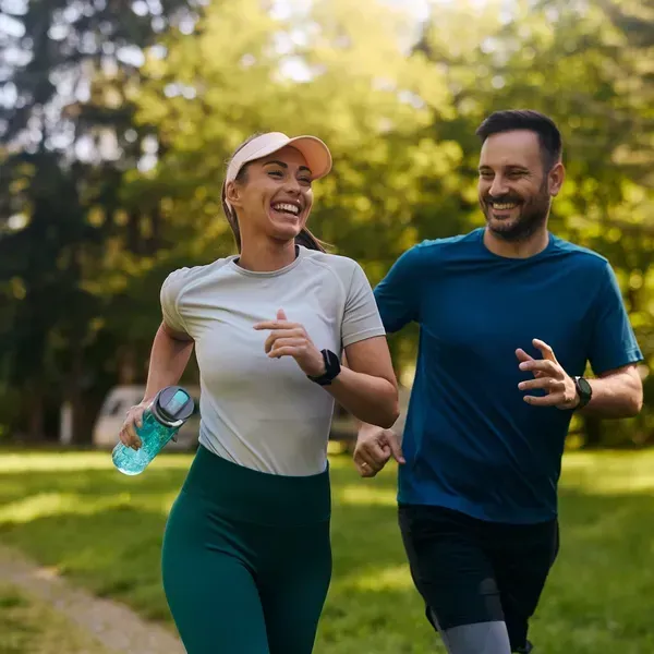 A man and a woman are running in a park.