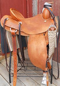 Brown leather western saddle on a black metal stand, with a wood and textile background.