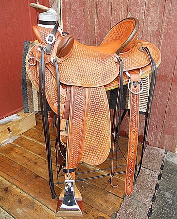 Brown leather Western saddle on a wooden stand with a red background.