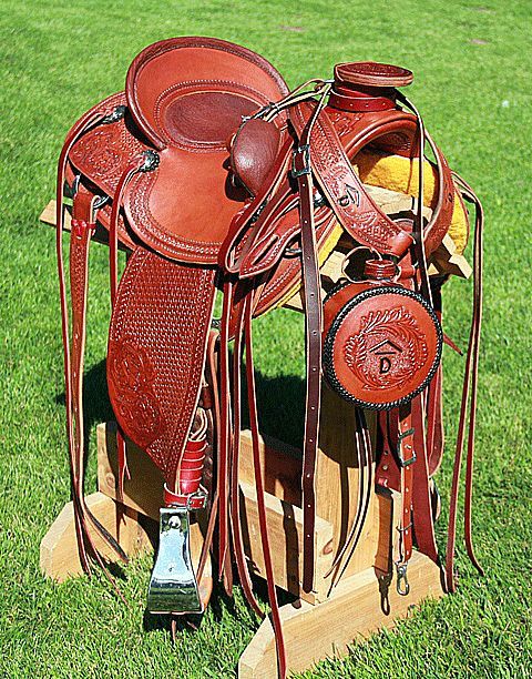 Brown leather Western saddle on wooden stand, outdoors.
