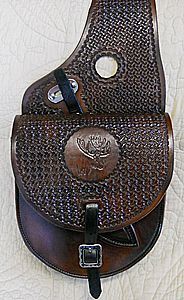 Brown leather saddle bag with woven texture, buckle, and embossed logo.