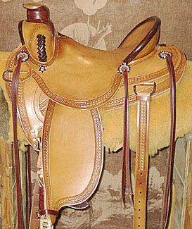 Tan leather Western saddle with brown trim, on a blurred background.
