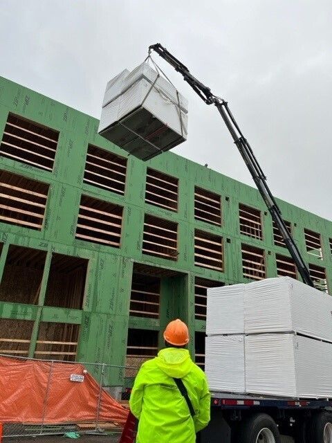 A man in a yellow jacket is standing in front of a building under construction