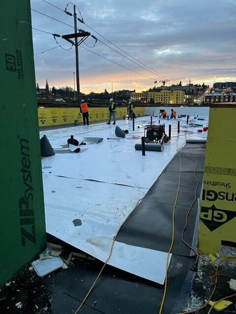 A group of people are working on a roof with a zipsystem sign in the foreground