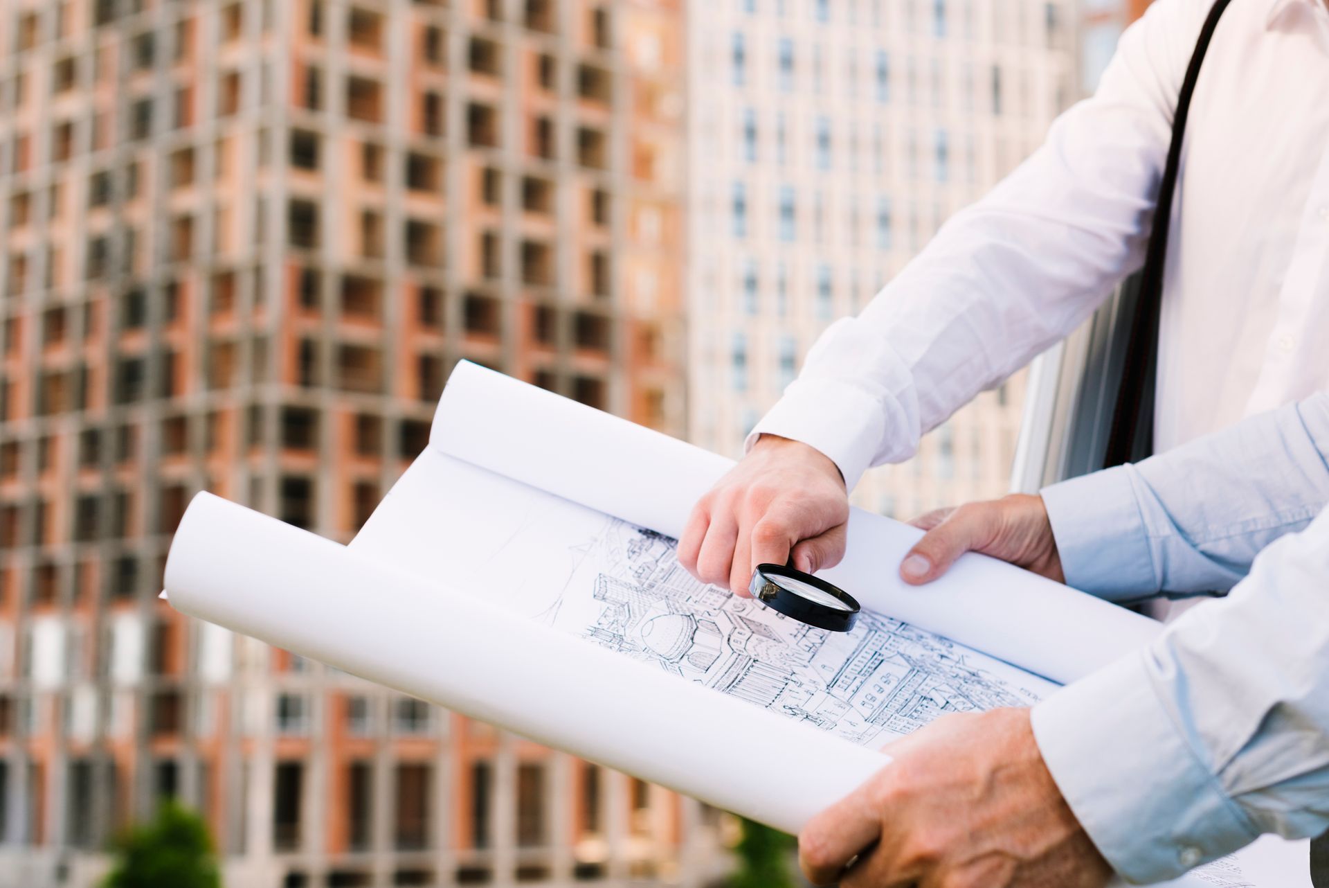 Two men are looking at a blueprint with a magnifying glass.