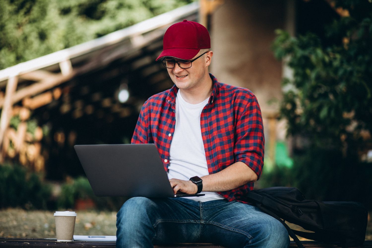 A man is sitting on a bench using a laptop computer.