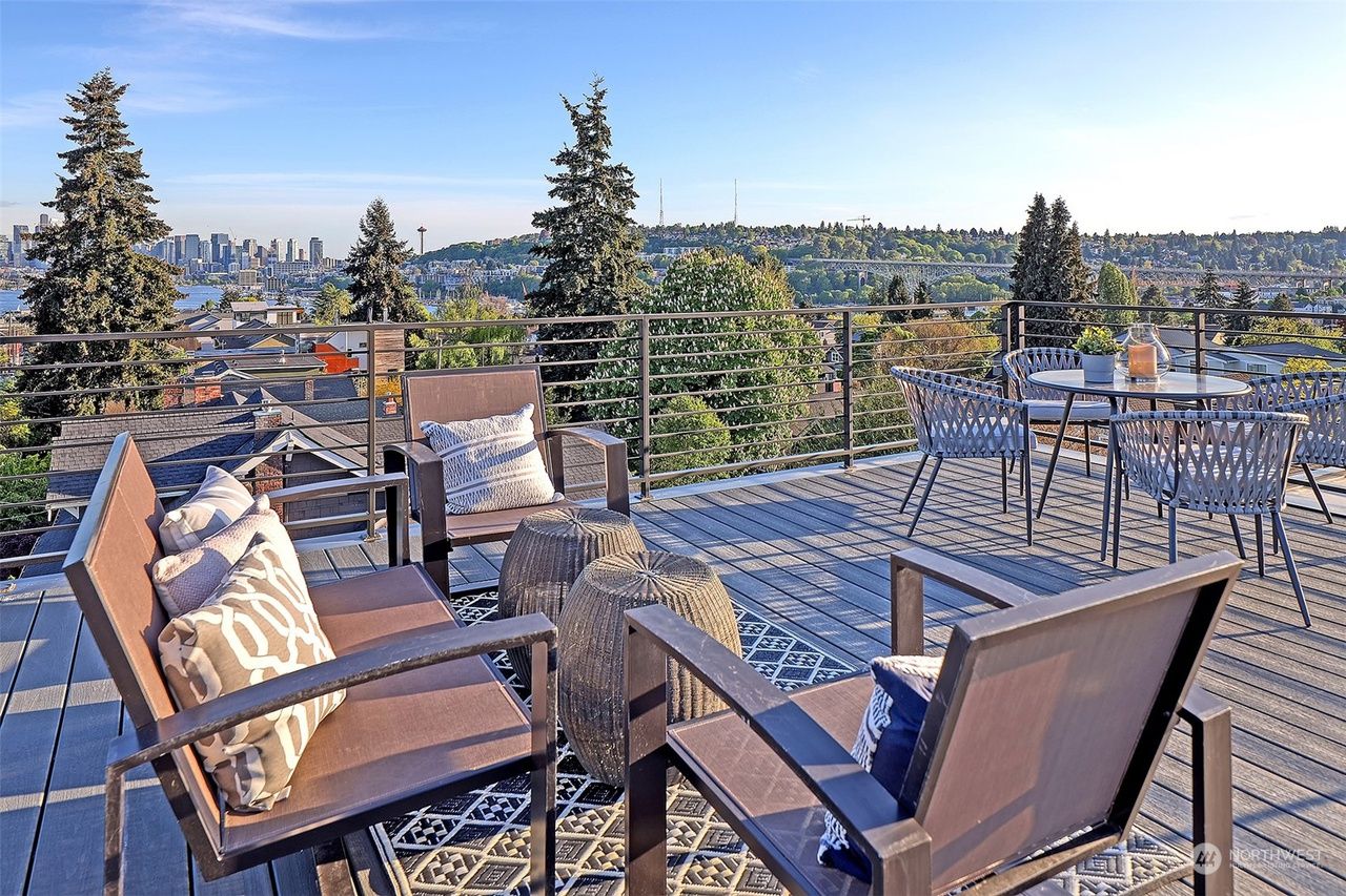 A patio with chairs and a table with a view of the city.