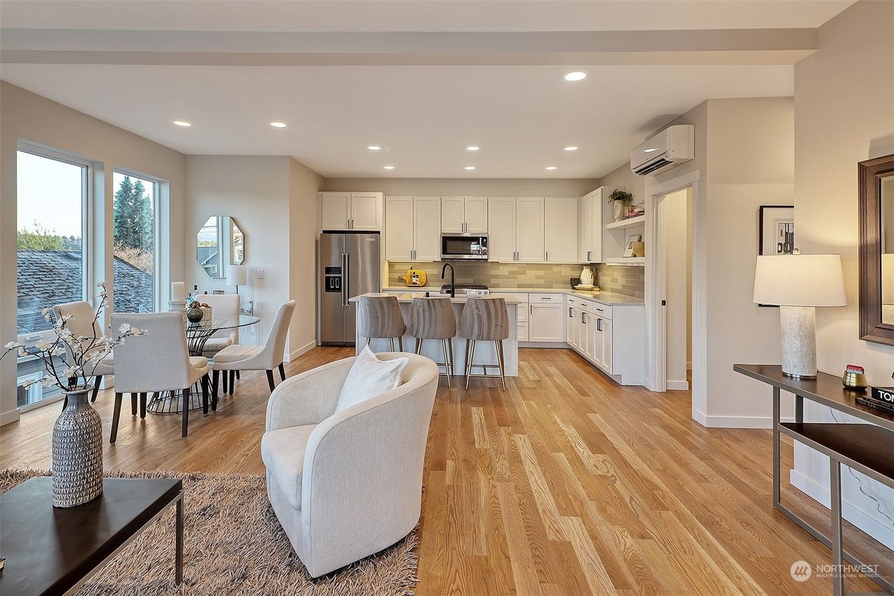 A living room and dining room in a house with hardwood floors and white cabinets.