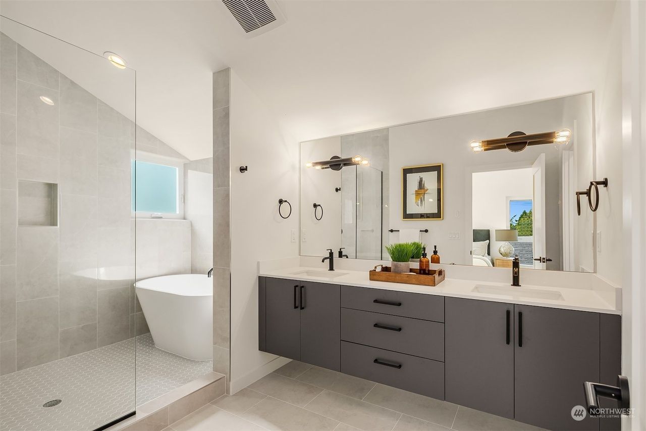 A bathroom with two sinks , a tub and a walk in shower.