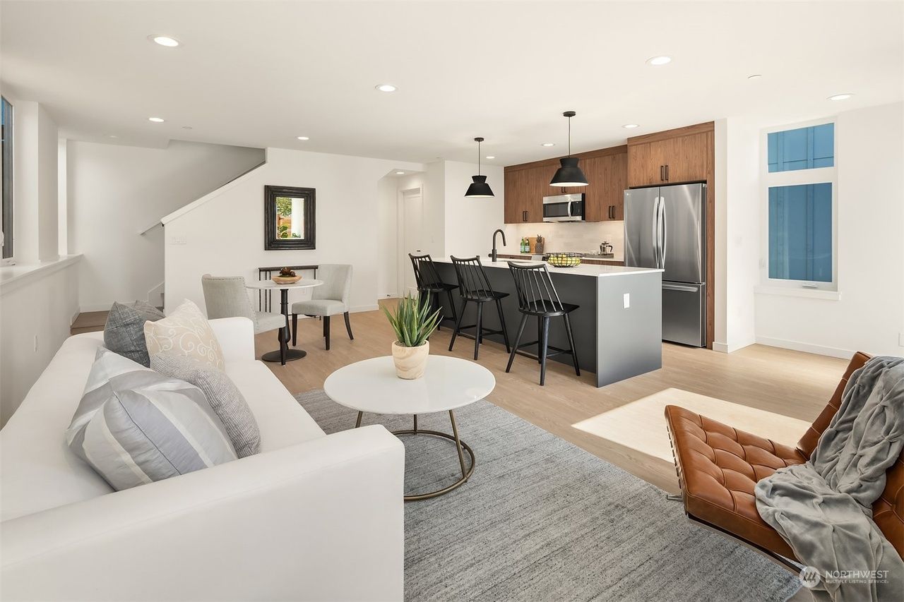A living room with a couch , table , chairs and a kitchen.