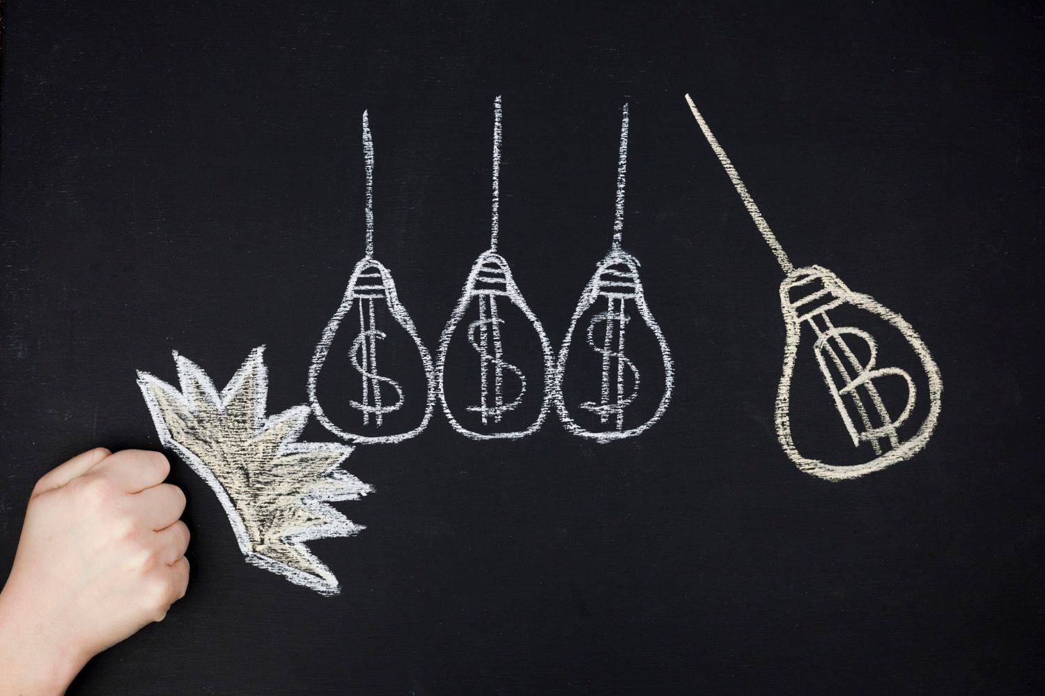 A person is drawing light bulbs with dollar signs on them