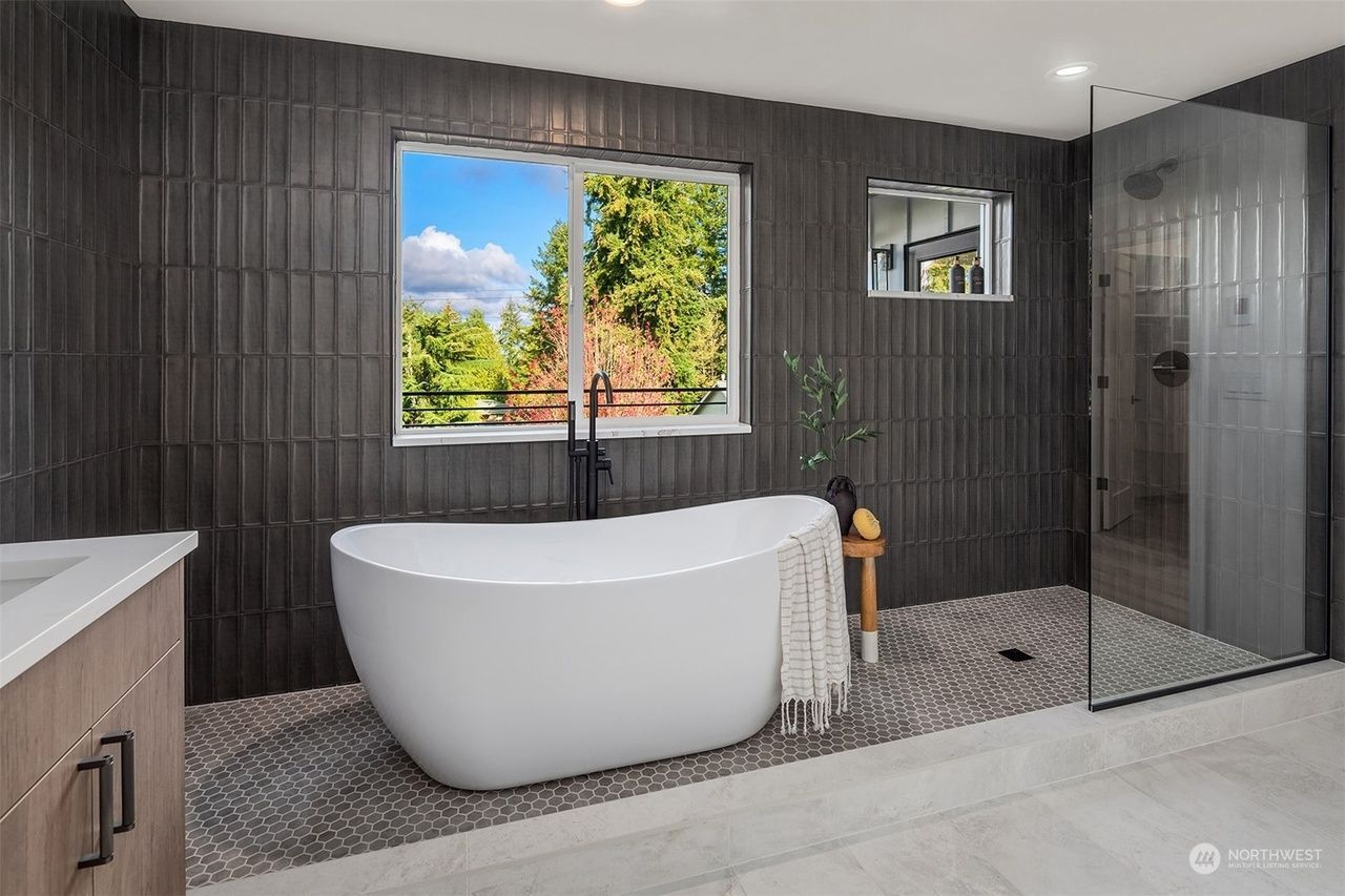 A bathroom with a bathtub , sink , shower and window.