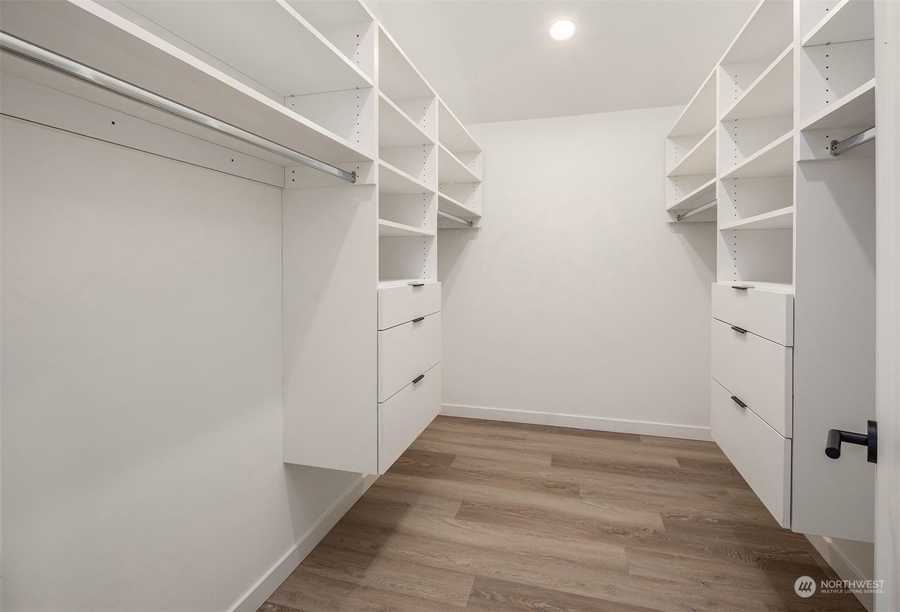 A walk in closet with lots of shelves and drawers.