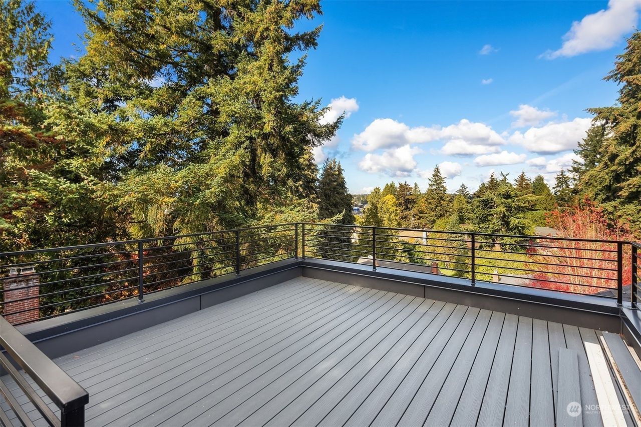 A rooftop deck with a view of trees and a blue sky