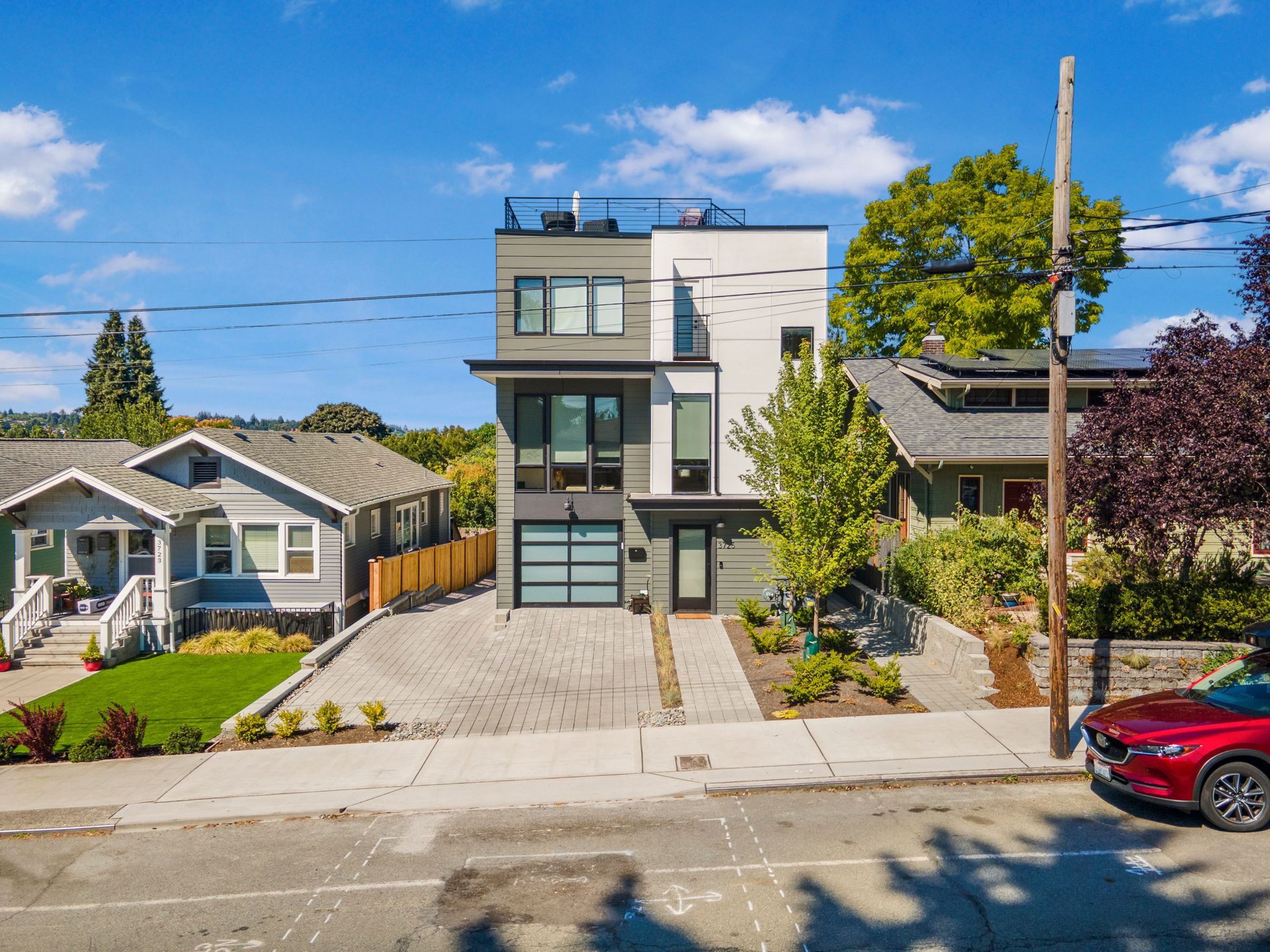 A red car is parked in front of a modern house