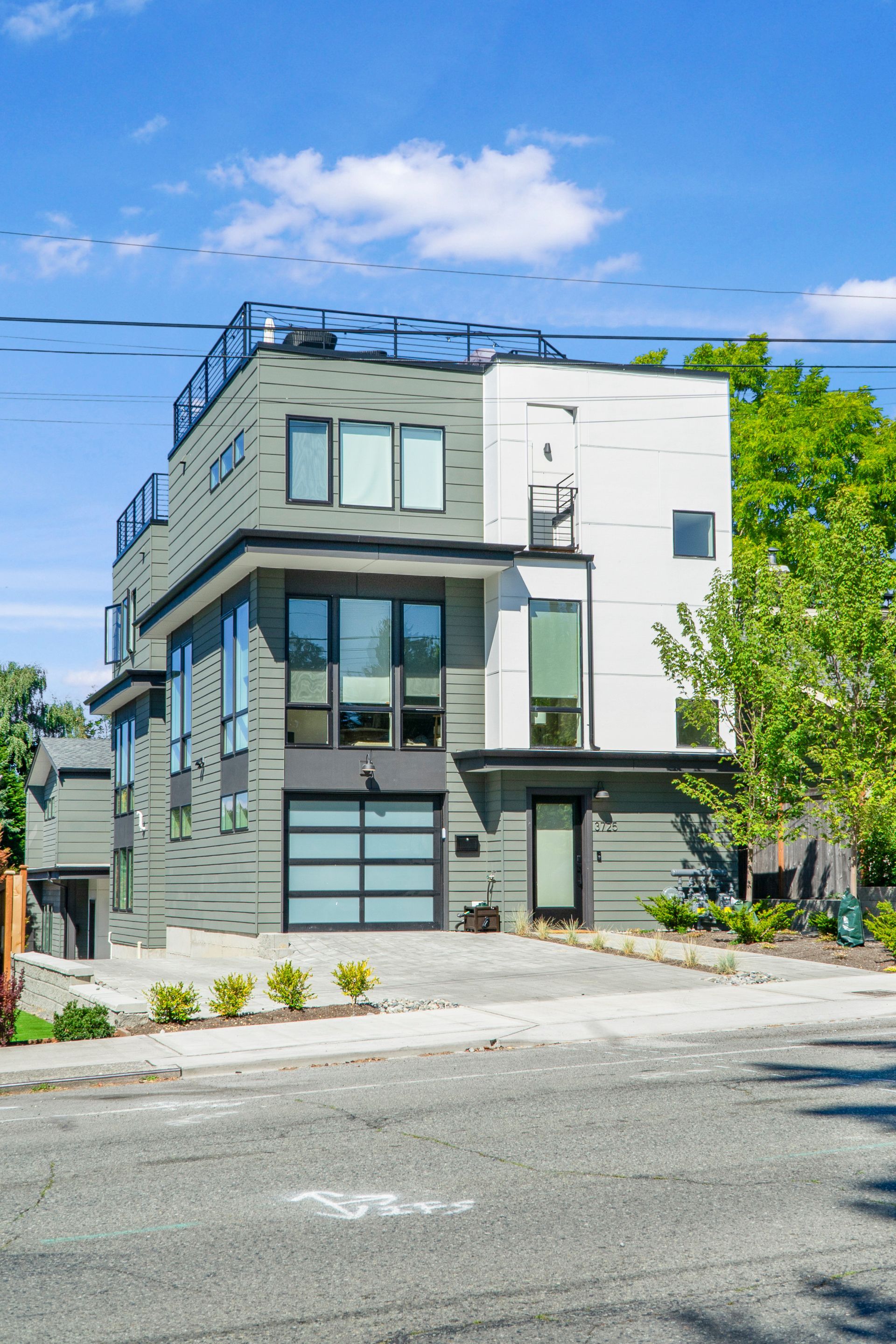 A modern apartment building with a garage and a rooftop deck.